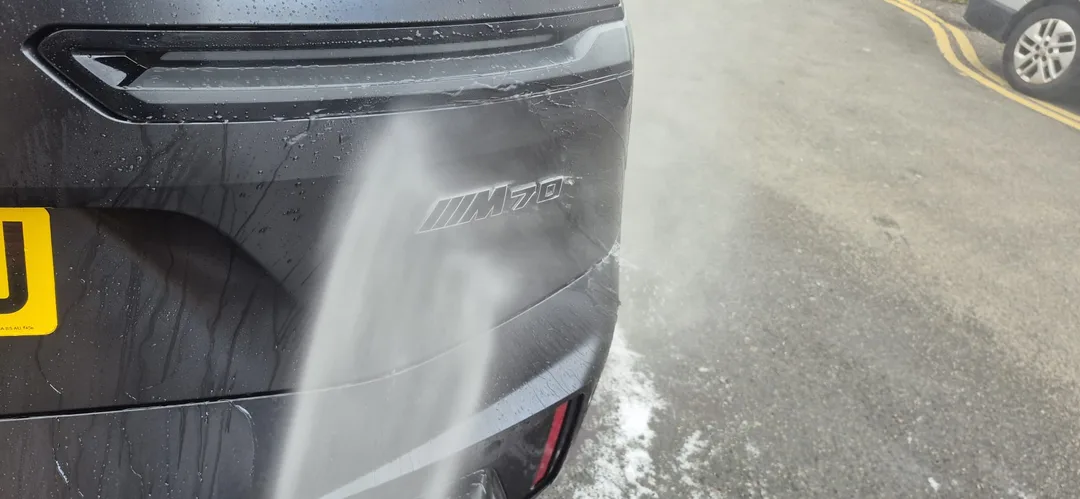 Chemicals being rinsed off Frozen Deep Grey BMW iX M70 at DMD Car Detailing in Paisley near Glasgow